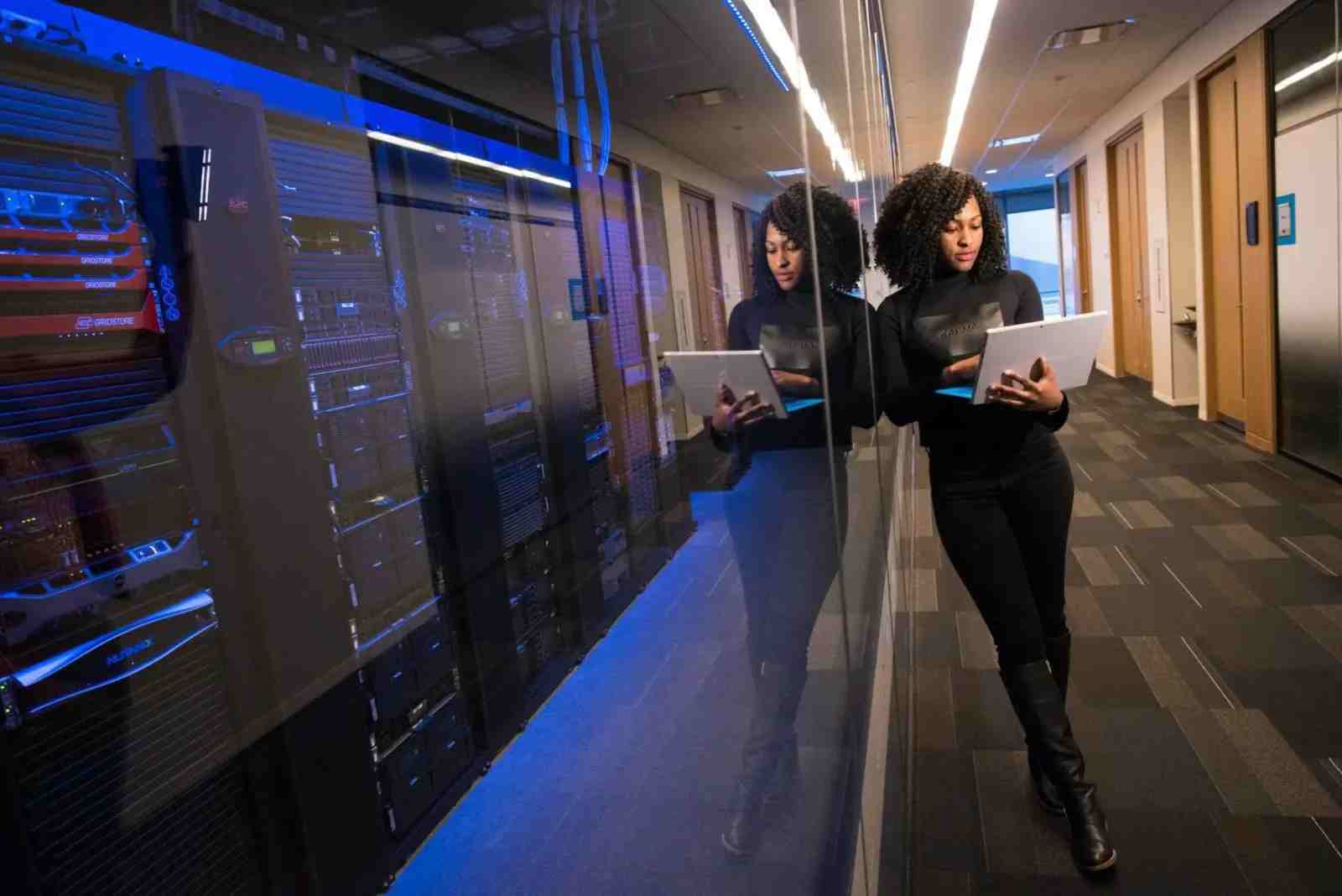 Woman on laptop next to server room