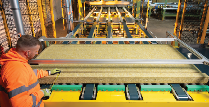 Isoclad production operative aligning mineral wool core on the panel manufacturing line.