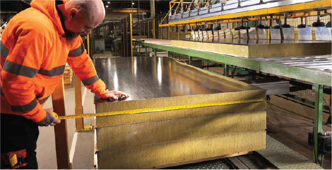 Isoclad production operative measuring a mineral wool panel core during manufacturing.