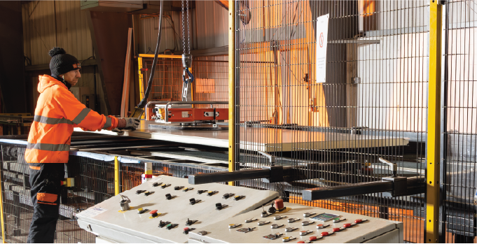 Isoclad production operative handling an insulated panel using lifting equipment on the CustomClad line.