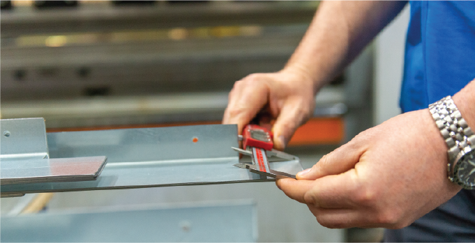 Isoclad team member checking the dimensions of a fabricated metal flashing.